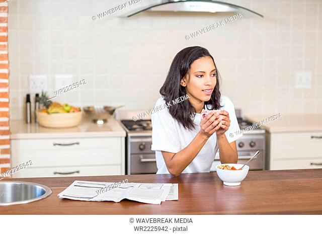 Smiling woman having breakfast in the kitchen