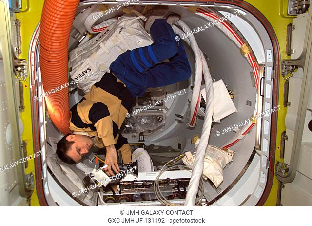 Cosmonaut Yuri I. Malenchenko, Expedition 7 mission commander, sets up a video camera to document a review of one of the Extravehicular Mobility Unit (EMU)...