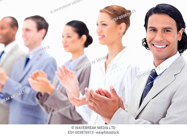Close-up of a business team smiling and applauding while looking towards the left side except for one against white background