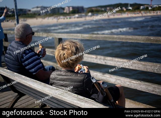 PRODUCTION - 28 September 2021, Mecklenburg-Western Pomerania, Ahlbeck: A couple takes a break on the pier at the beach of the Baltic resort Ahlbeck on the...