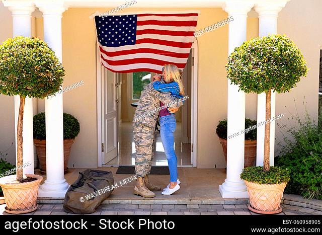 Caucasian couple embracing each other on soldier's return at the entrance with usa flag
