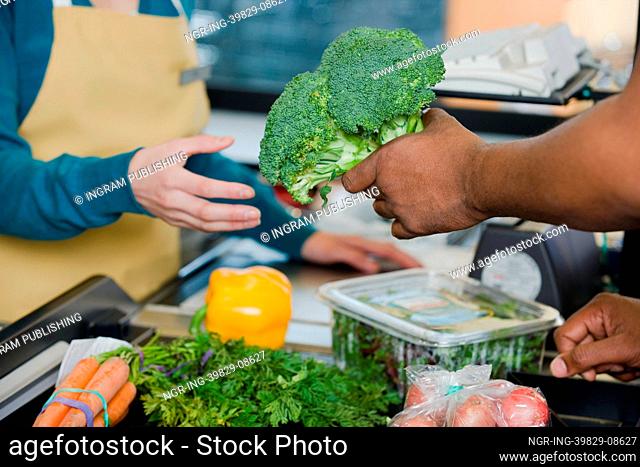 customer handing a sales assistant broccoli