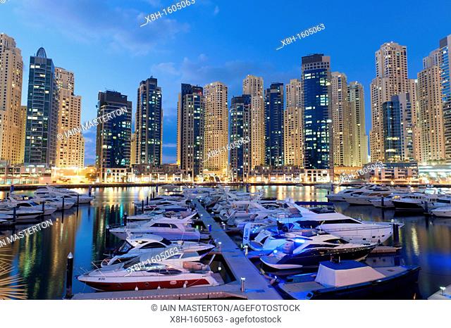 Boats in harbour in the evening at Yacht Club Marina with apartment towers to rear in New Dubai in United Arab Emirates