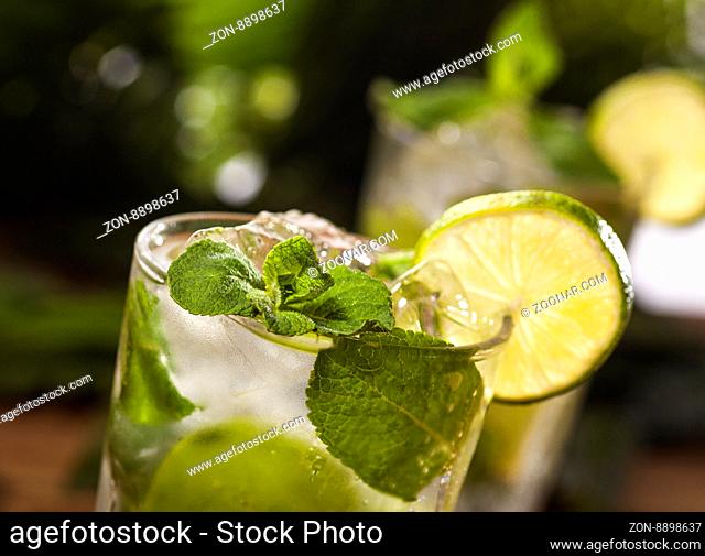 Mojito cocktail on wooden and green tropical leaves background