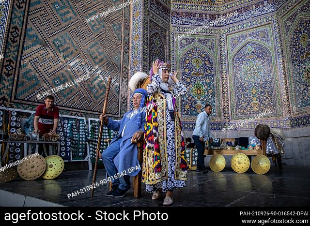 26 September 2021, Uzbekistan, Samarkand: Uzbeks wear traditional dresses for a souvenir photo at the historical landmark of Registan in Samarkand