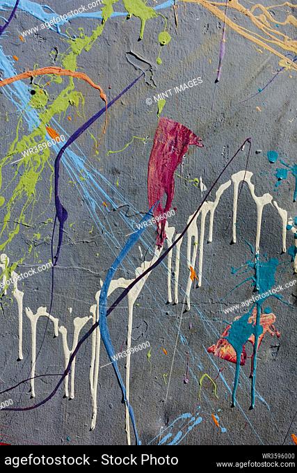 Colorful graffiti paint splattered and dripping on urban wall, close up
