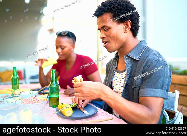 Young man eating taco lunch at patio table