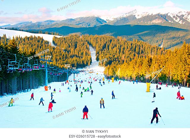 People skiing and snowboarding on a slope at ski resort