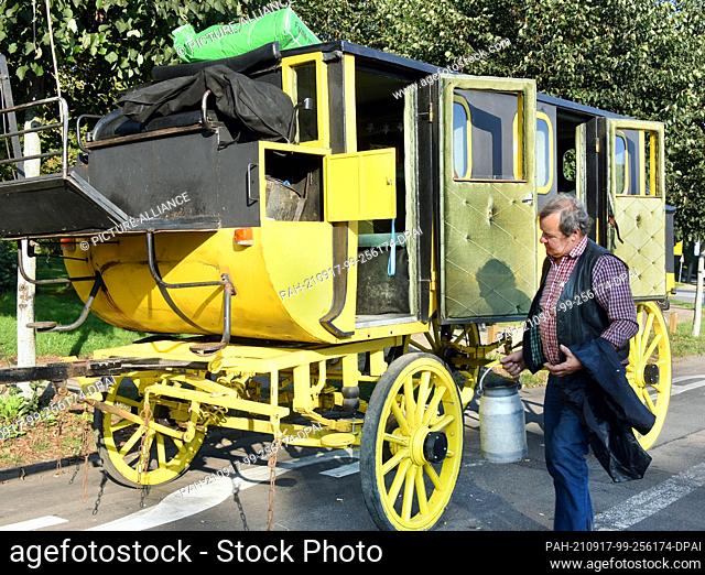 14 September 2021, Saxony, Leipzig: The coachman Siegfried Händler brings a jug of water for his horses to his historic stagecoach