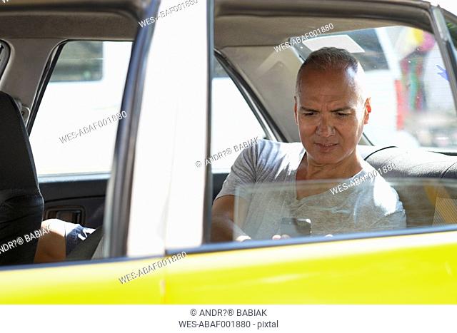 Mexico, Puerto Vallarta, tourist sitting in taxi looking at smartphone