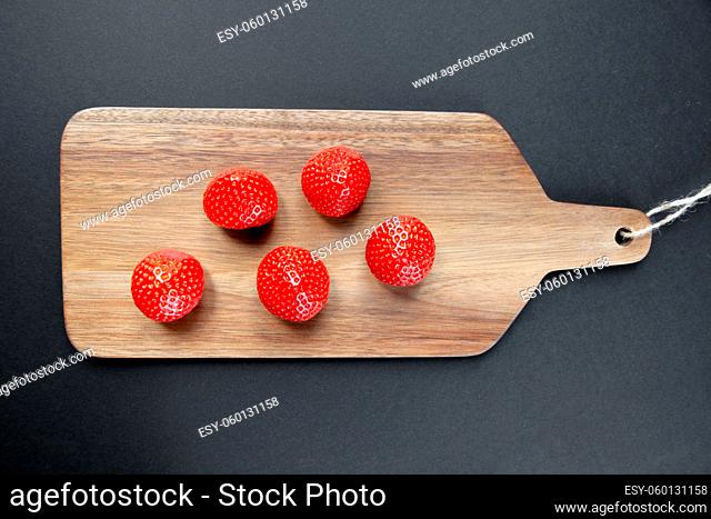 Strawberries on a wooden cutting board. Black background. Top view
