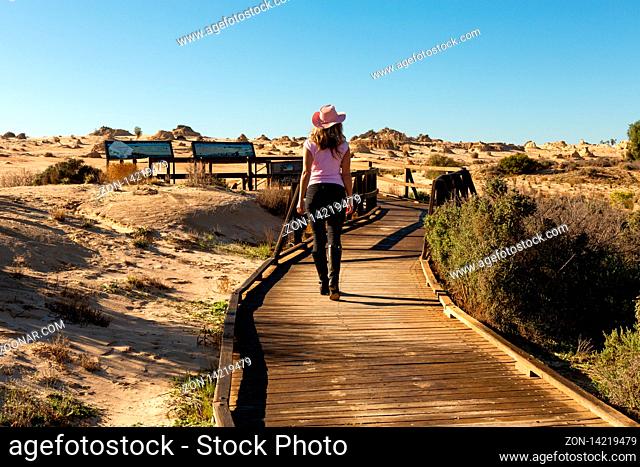 Tourist visitor walks along the timber boardwalk to the desert and Mungo National Park viewing platforms