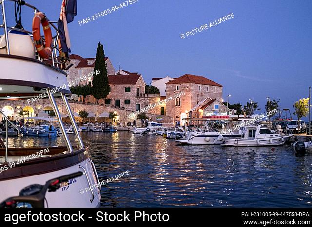 PRODUCTION - 27 September 2023, Croatia, Bol: The harbor with boats, cafes and restaurants in Bol on the island of Brac in the evening