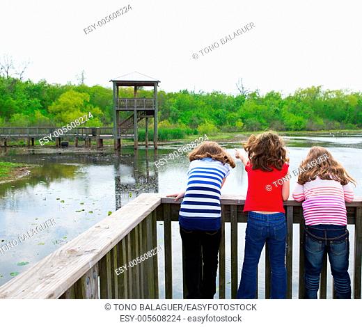 kid children girls looking and pointing at park lake in Texas rear view