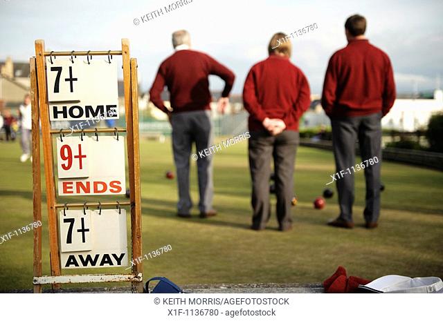 Men playing a game of lawn green bowls on a summer evening, Aberystwyth Wales UK