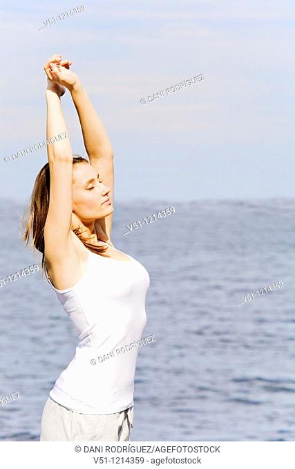 Portrait of a brunette woman stretching by the sea