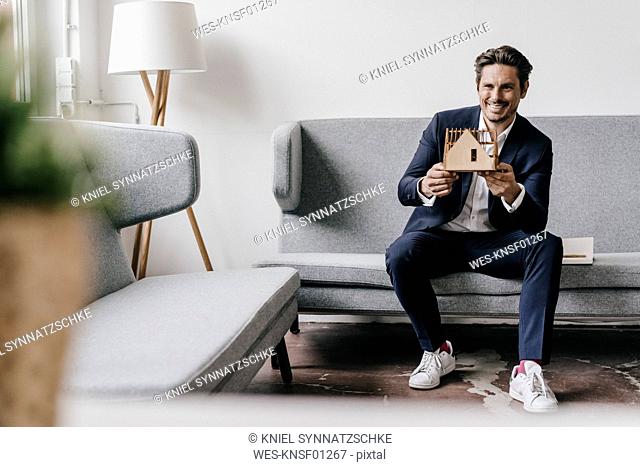 Smiling architect on couch holding architectural model