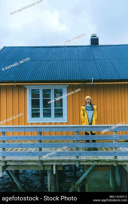 Young woman with yellow raincoat in Norway, Lofoten, fishing village