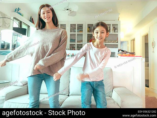 Happy mother and daughter dancing at home