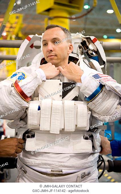 Astronaut Randy Bresnik, STS-129 mission specialist, dons a training version of his Extravehicular Mobility Unit (EMU) spacesuit in preparation for a spacewalk...