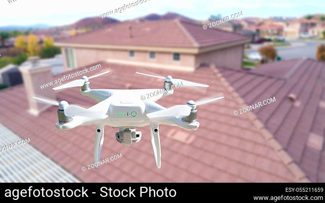 Unmanned Aircraft System (UAV) Quadcopter Drone In The Air Over House Inspecting the Roof
