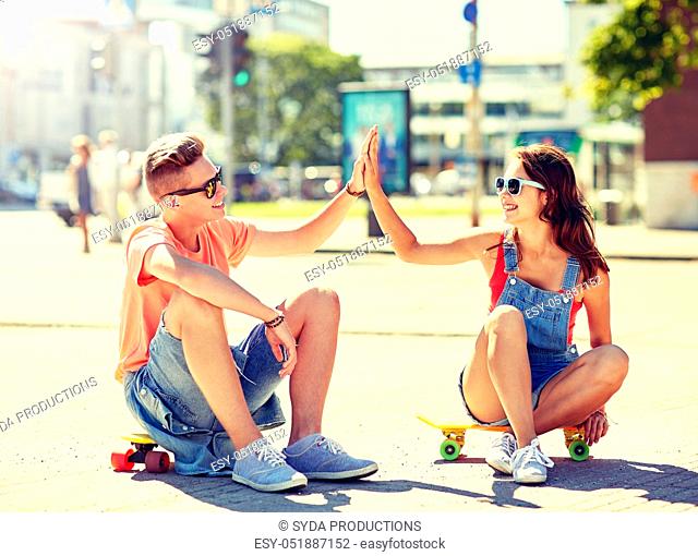 teenage couple with skateboards on city street