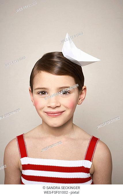 Portrait of smiling little girl with paper boat on her head