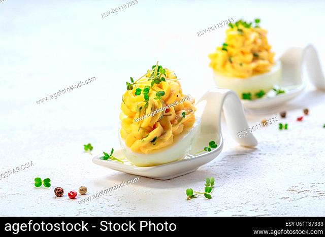 Half of the egg is filled with egg, cheese, arugula sprouts and cream sauce. Concept of homemade snacks for Easter. Copy space