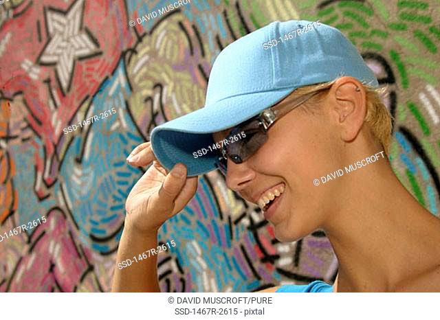 Side profile of a young woman smiling wearing sunglasses