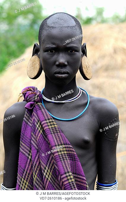 Mursi girl without lip plate but with ear disks. Mursi or Mun people are pastoralist and reside in Debub Omo Zone in the border of South Sudan