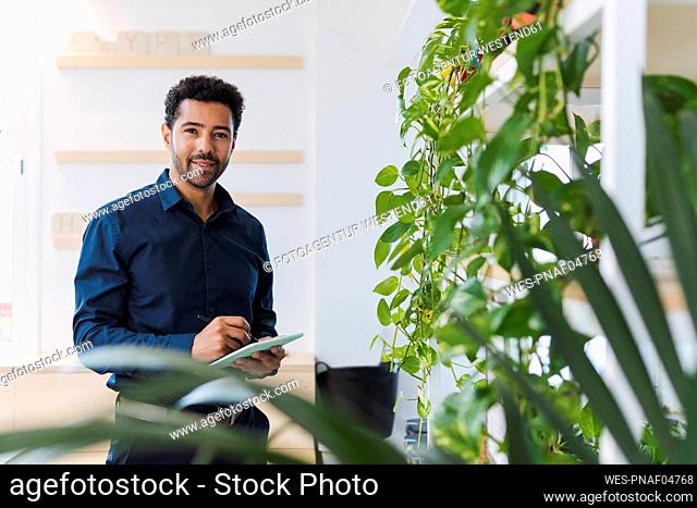 Portrait of businessman in office using digital tablet