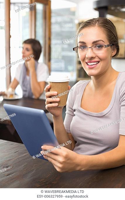 Pretty blonde enjoying a coffee using tablet pc at the coffee shop