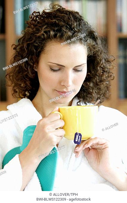 woman fighting against cold with tea and hot-water bottle