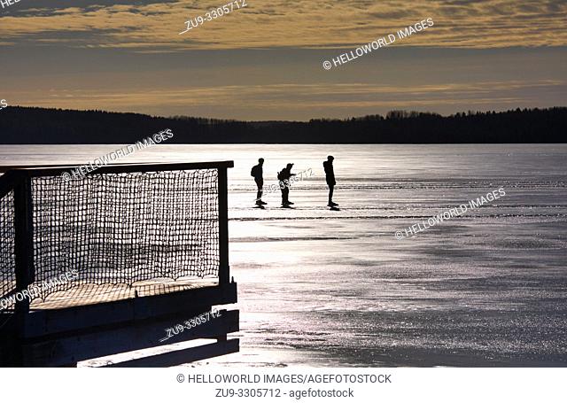 Three long distance ice skaters silhouetted on Lake Malaren, Sigtuna, Sweden, Scandinavia