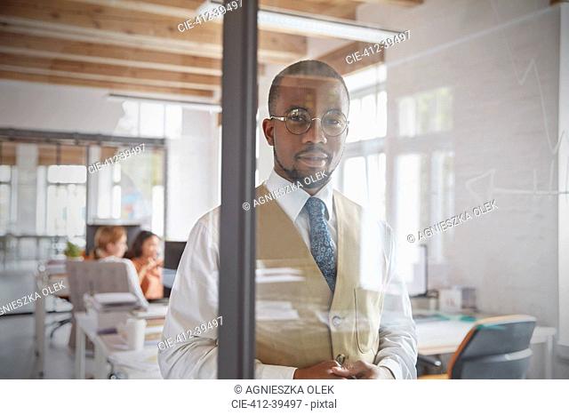 Portrait confident businessman at window in office