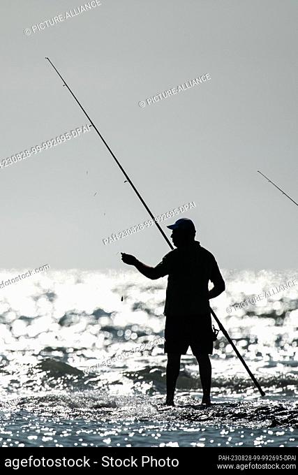 SYMBOL - 22 August 2023, France, Plage Des Phoques: A man is fishing on the coast of the Atlantic Ocean on a stretch of beach. Photo: Silas Stein/dpa