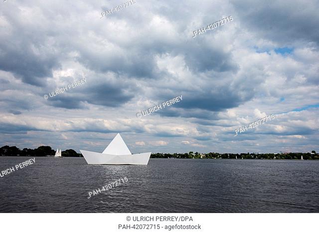 A converted pedal boat looking like a paper ship drives on the Alster lake under a cloudy sky in Hamburg, Germany, 27 August 2013