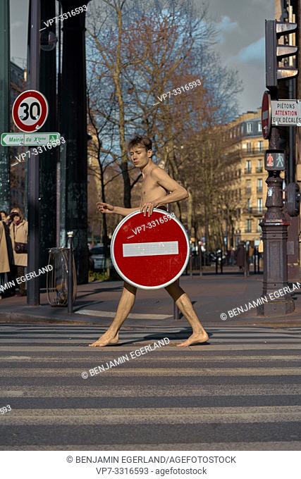 young naked man with prohibition sign walking at street, in Paris, France
