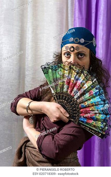young woman hiding her face behind a fan colored