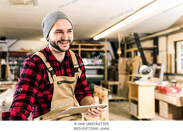 Smiling worker holding tablet in workshop