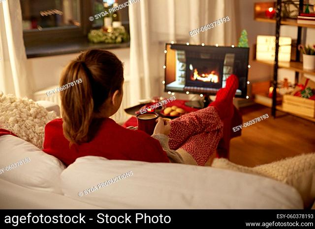 woman watching tv and drinking coffee on christmas