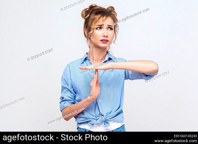 Please break! Time out, stop sign. Young adult blonde girl showing warning sign. Studio shot on gray background