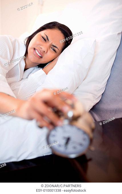 Woman getting pain in the ears by alarm clock