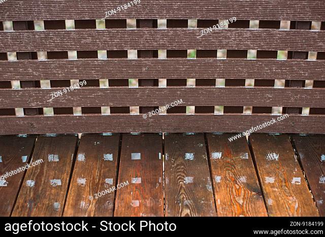 Wooden wet bench in the summer park. Closeup with reflections