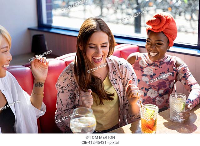 Happy, excited young women drinking cocktails in restaurant