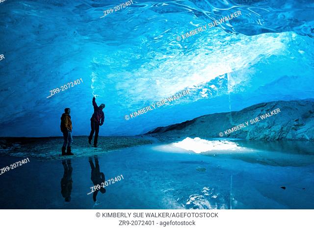 Two people standing inside an ice cave at Nigardsbreen Glacier, at Jostedalsbreen, Europe's largest ice cap, West Coast Fjords, Norway