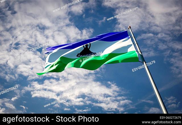 Beautiful national state flag of Lesotho fluttering at sky background. Low angle close-up Lesotho flag 3D artwork