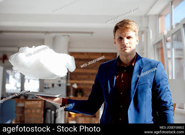 Businessman holding tablet PC under levitating cloud network in office