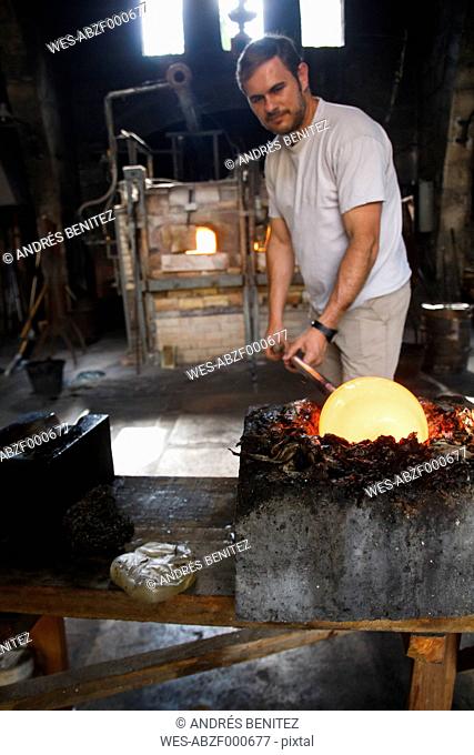 Man putting molten glass in a mold in a glass factory