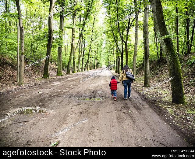 Mom and 4 year old son walking in a street in the forest